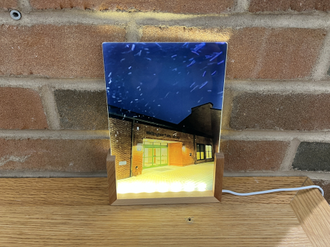 lit up snowy photo of the library in front of a brick wall