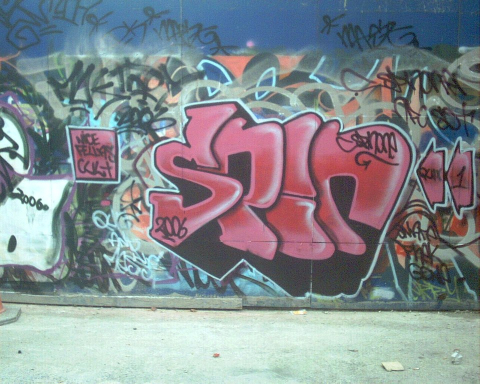 Graffiti on a wall in a city that reads "spin"
