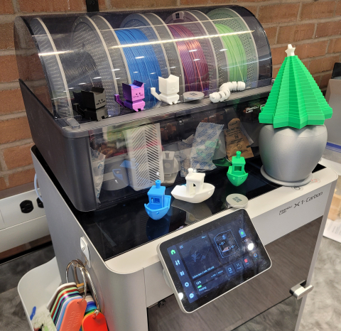 A collection of 3D printed cats, boats, and a collapsible tree on top of a Bambu X1Carbon 3D Printer.