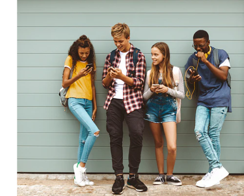 Four teens looking at their phones and laughing together.