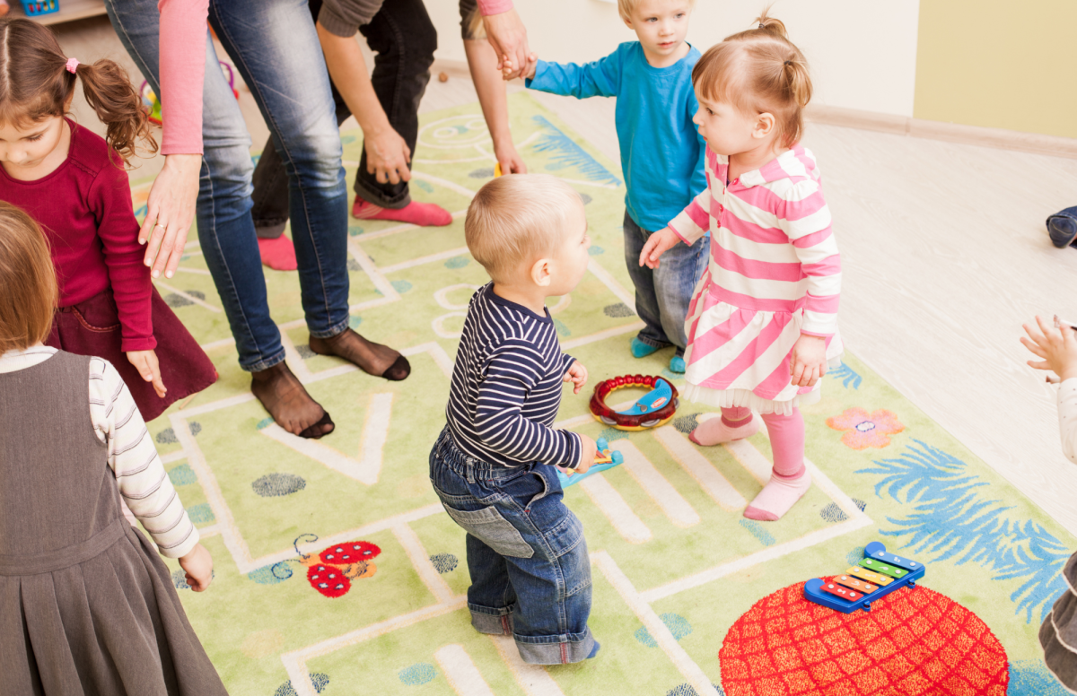 toddlers dancing around with adults near by to catch