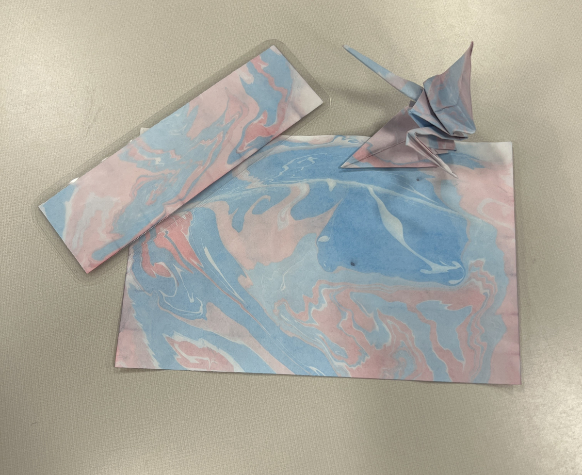 Blue and pink marbled paper sheet, paper crane, and a bookmark.