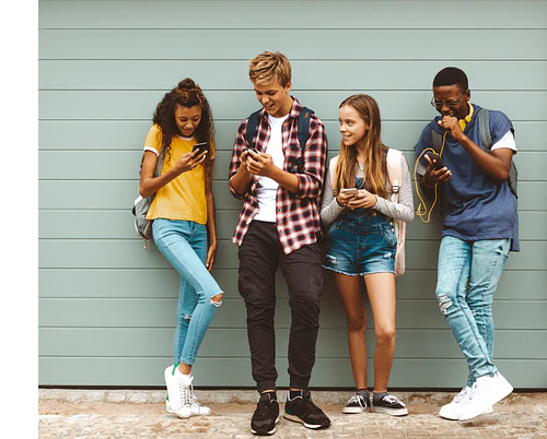 Four teens looking at their phones and laughing together.